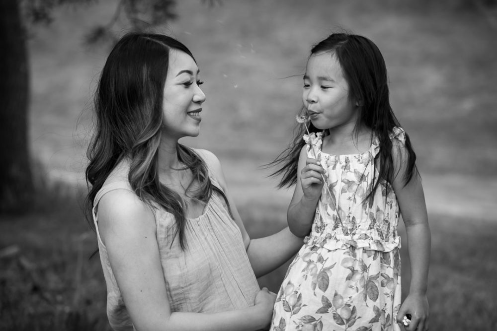 Outdoor family photos - young girl blowing dandelions with mom by Paper Bunny Studios Edmonton