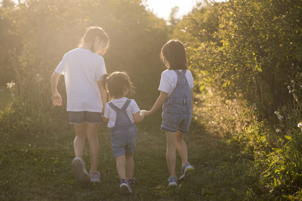 Edmonton Fall family photos in apple orchard - documentary family portrait of sisters walking away by Paper Bunny Studios