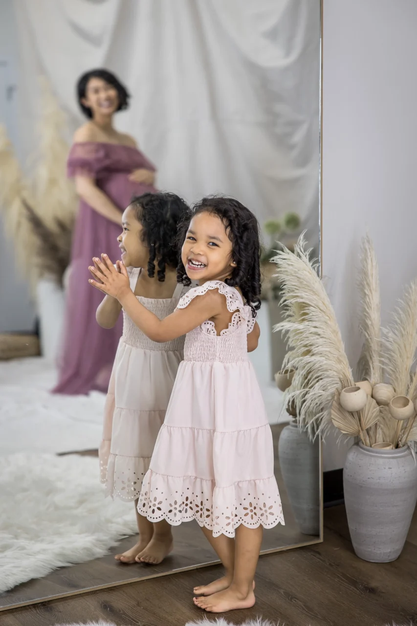 Cute portrait of daughter by mirror with mom smiling in reflection by Edmonton Family photographer Paper Bunny Studios