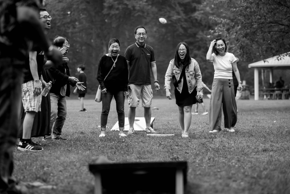 Documentary family reunion photography of grown ups playing bean bag toss by Paper Bunny Studios Edmonton