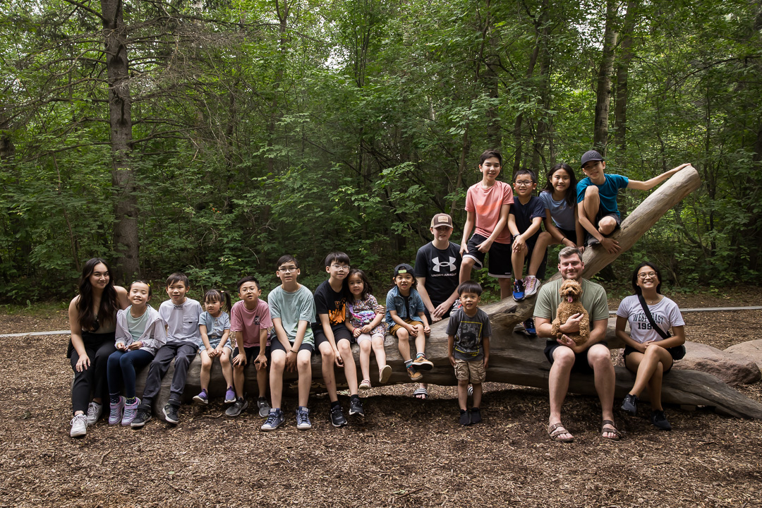 Extended family gathered on a fallen tree at Laurier Park by Edmonton family photographer Paper Bunny Studios