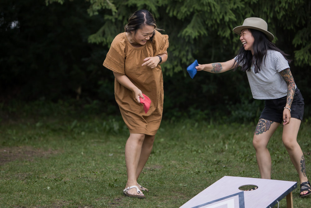 Documentary family reunion photography of grown ups laughing over bean bag toss by Paper Bunny Studios Edmonton