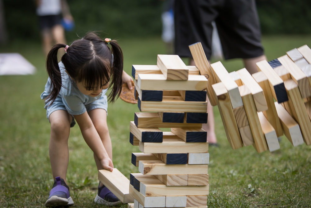 Documentary family reunion photography of little girl playing garden jenga by Paper Bunny Studios Edmonton