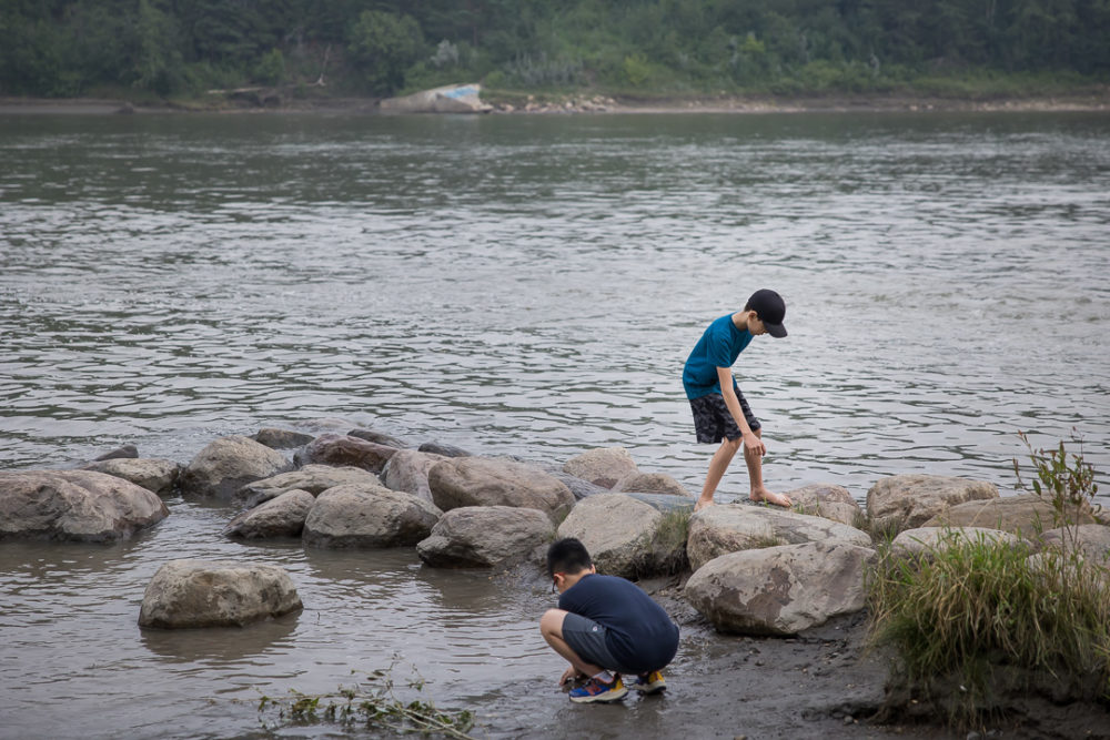 Documentary family reunion photography of kids playing on rocks by water by Paper Bunny Studios Edmonton