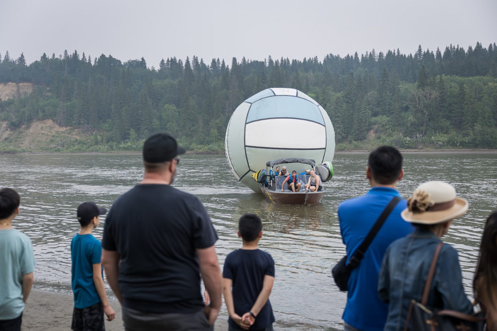 Documentary family reunion photography of people on shore watching those on an inflatable on water by Paper Bunny Studios Edmonton