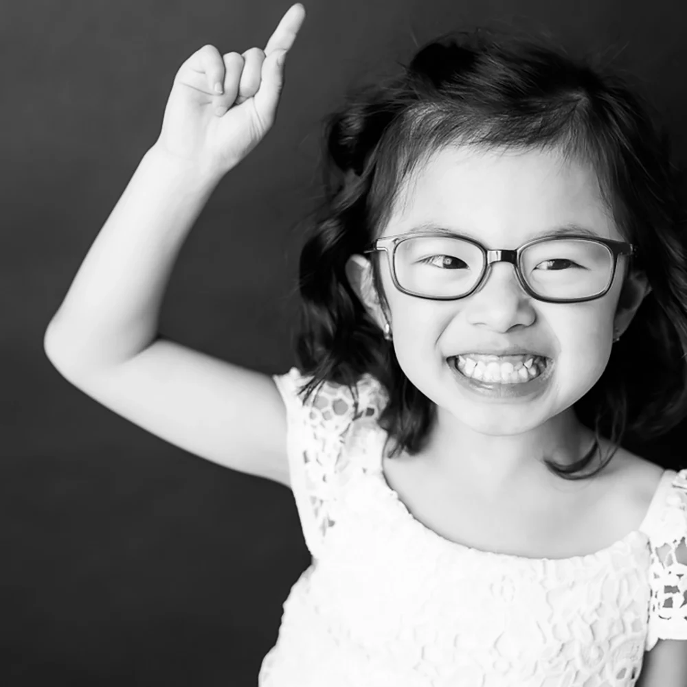 fun black and white portrait photo of young girl wearing glasses by Edmonton Family Photographer Paper Bunny Studios