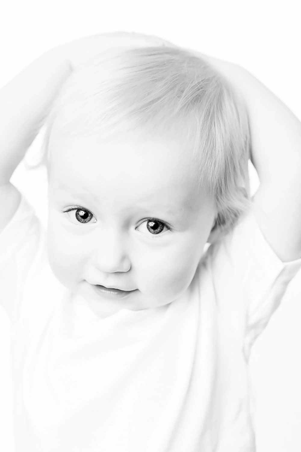 Black & white portrait of toddler with hands behind head by Edmonton family photographer Paper Bunny Studios