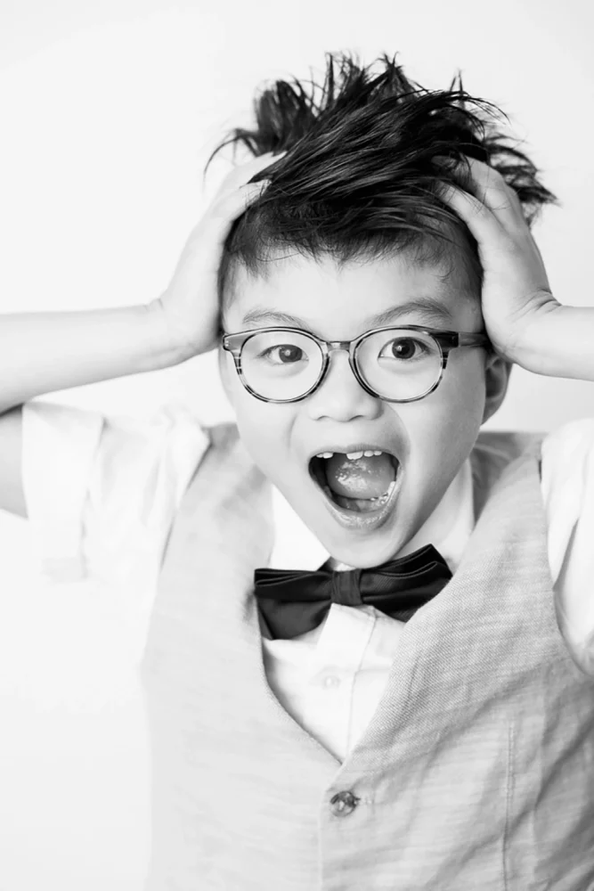 black and white portrait photo of young boy pulling a home alone expression by Edmonton Family Photographer Paper Bunny Studios