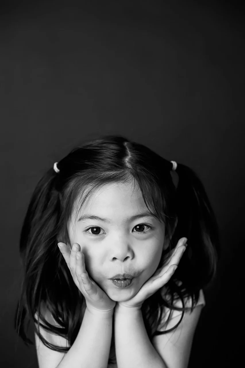 black & white portrait of little girl striking a pose with face in hands by Paper Bunny Studios Edmonton familiy photographer