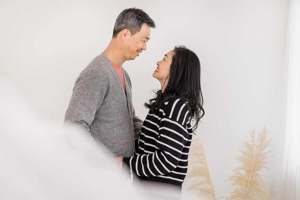 Artistic portrait of husband and wife smiling at one another by Edmonton Family Photographer Paper Bunny Studios