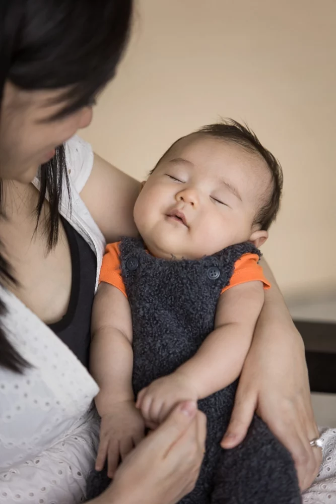 Calgary documentary family photo shoot of newborn baby boy asleep in mom's arms by Paper Bunny Studios