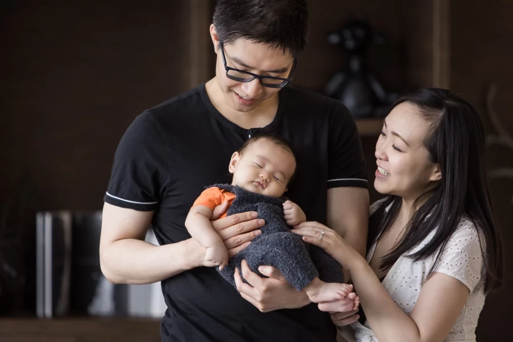 Calgary newborn photo shoot with baby boy held by dad by Paper Bunny Studios