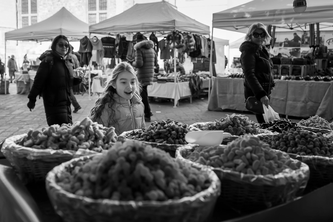 Black & white photo of young girl excited about candy stall in Florence by Edmonton family photographer Paper Bunny Studios