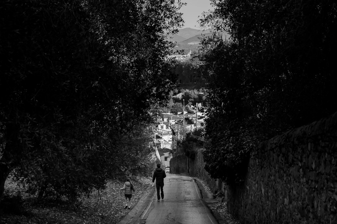 Black & white photo of dad & daughter walking along a forested road in Florence by Edmonton family photographer Paper Bunny Studios