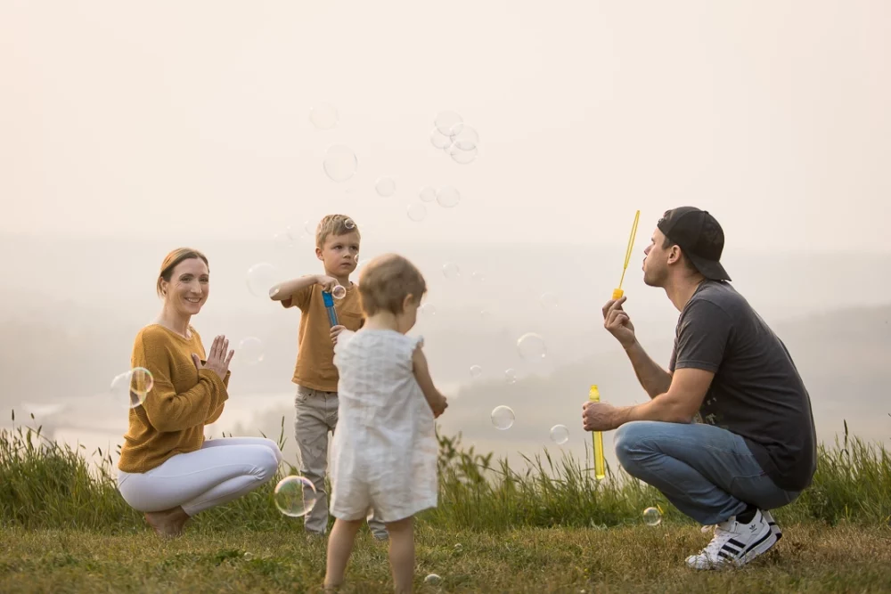 outdoor yoga family photo session by Paper Bunny Studios with dad blowing bubbles to entertain kids