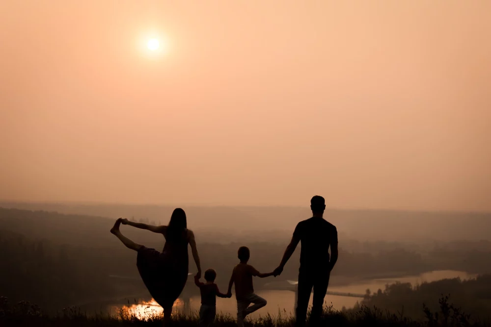 sunset silhouette of family in Edmonton with mom doing a standing yoga pose by Paper Bunny Studios