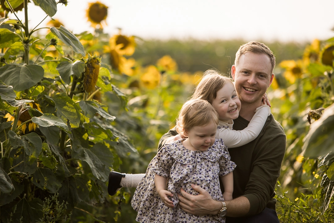 Edmonton family photos in sunflower field with  dad & daughters by fine art family photographer Paper Bunny Studios