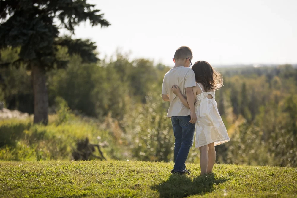 Outdoor family photo of siblings cuddling one another by Paper Bunny Studios Edmonton